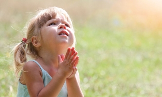 Mädchen betet in der Natur mit gefalteten Händen 