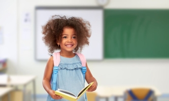 Mädchen mit Rucksack und Buch in Klassenzimmer 