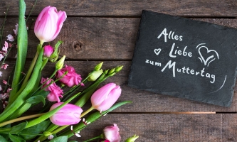 Blumenstrauß und Schiefertafel mit Aufschrift Alles Liebe zum Muttertag 