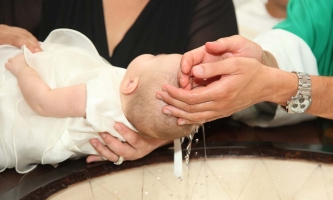 Ein Baby wird übers Taufbecken gehalten.