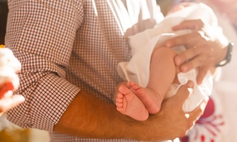 Mann in Kirche hält Baby im Arm 