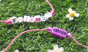 zwei Perlenarmbänder mit Schrift friends forever auf einer Blumenwiese