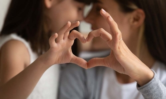 Tochter und Mutter formen mit ihren Händen ein Herz.