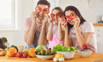 Eltern und Kind halten sich Paprikaringe vors Gesicht 