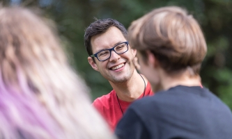 Ein junger Salesianer Don Boscos unterhält sich ausgelassen mit zwei Jugendlichen.