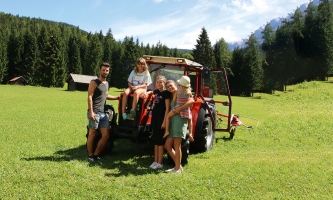 Die gesamte Pflegefamilie steht auf dem Feld vor dem Traktor.