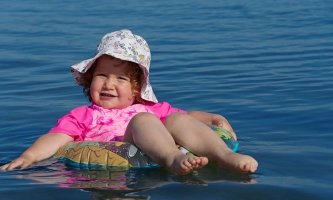 Ein Kleinkind lässt sich zufrieden im Schwimmring treiben.