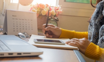 Hände von Frau mit Notebook, Handy und Tischkalender 