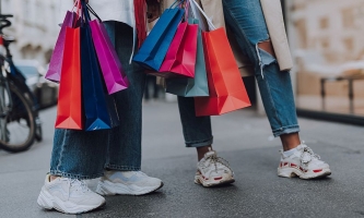 Beine von zwei jungen Frauen in Jeans und Turnschuhen mit vielen Einkaufstaschen