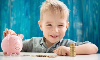 Kind lachend mit Sparschwein und Münzen 