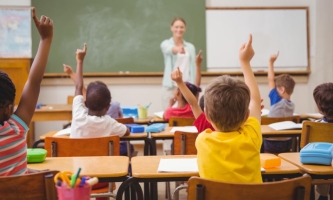 Schülerinnen und Schüler im Klassenzimmer melden sich 