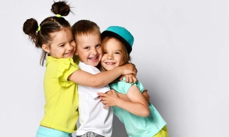 Drei Kinder umarmen sich und lachen.