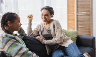 Eine Mutter und ihre Tochter sitzen auf dem Sofa und unterhalten sich.