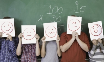 Schulkinder halten sich Blätter mit Smileys vors Gesicht