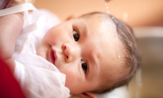 Baby über dessen Kopf Wasser rinnt 