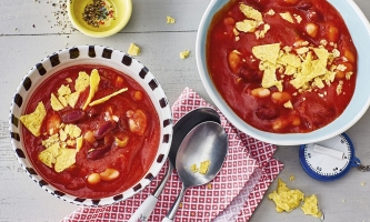 zwei Schälchen mit Bohnensuppe und Tacochips mit Löffeln 