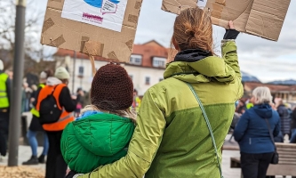 Mutter und Kind halten bei einer Demonstration Plakate hoch