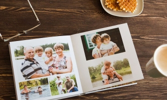 Fotoalbum mit Familienfotos auf Tisch mit Brille, Keksen und Kaffeetasse 