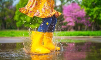 Mädchen in Gummistiefeln tanzt im Regen