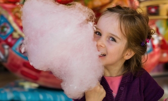 Mädchen mit Zuckerwatte vor Verkaufsstand auf Fest 