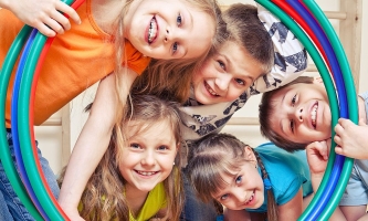 Kinder in Turnhalle schauen glücklich durch Hullahoop-Reifen 