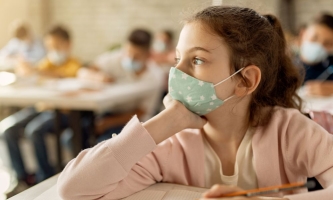 Mädchen in Klassenzimmer schaut traurig aus dem Fenster 