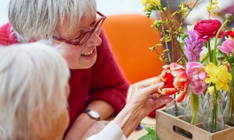 Seniorin und Gartentherapeutin Bärbel Zirker betrachten mitgebrachte bunte Blumen 
