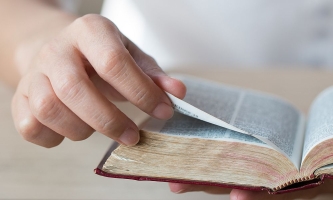 Hand blättert in Bibel beim Vorlesen in der Familie 