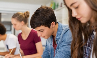 Schülerinnen und Schüler in Klassenzimmer schreiben Prüfung