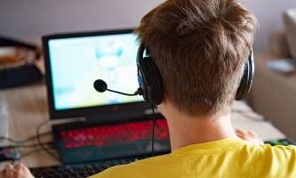 Jugendlicher an PC mit Headset bei Online-Spiel 