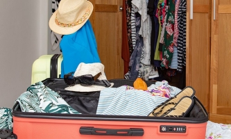 halb gepackter Koffer vor offenem Kleiderschrank 