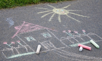 Mit Wachsmalkreide auf die Straße gemaltes Haus mit Garten 