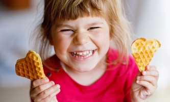 Kind hält fröhlich zwei Waffelherzen in den Händen 