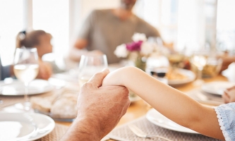 Menschen geben sich die Hände bei Tischgebet vor dem Essen mit Familie 