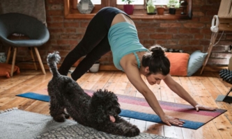 Frau und Hund machen im Yoga den Herabschauenden Hund 