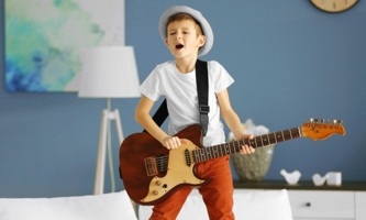 Junge singend mit E-Gitarre im Wohnzimmer