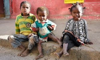 Drei Kinder sitzen auf Gehsteig in Madagaskar 