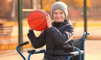 Junge im Rollstuhl hält Basketball 