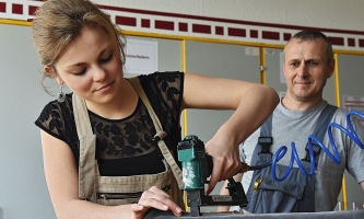 Junge Frau arbeitet mit elektrischem Gerät an Möbelstück