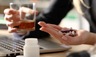 Frau am Schreibtisch mit Alkohol und Tabletten 