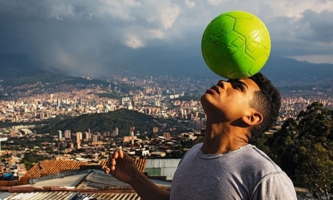 Junge mit Fußball vor Stadtkulisse von Medellin 