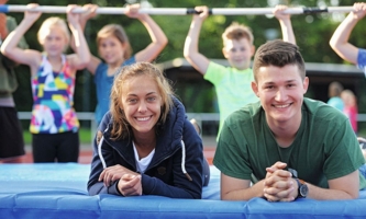 Zwei Jugendliche liegen auf Sportmatte und lachen in die Kamera 