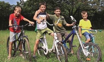 Vier Jungen mit Fahrrädern auf einer Wiese 