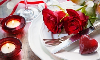 Tischdekoration mit Kerzen, roten Rosen und Herz 