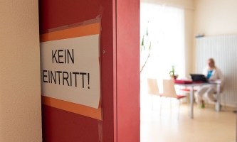 Schild Kein Eintritt! dahinter Raum mit Frau am Schreibtisch 