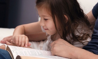 Mädchen liest mit Vater in Bibel 