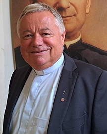 Salesianerpater vor Bild von Don Bosco