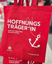 rote Stofftasche mit wei&szlig;em Aufdruck Hoffnungstr&auml;ger*in, Anker und Don Bosco Logo