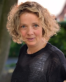 Frau mit kurzen blonden Locken im Garten